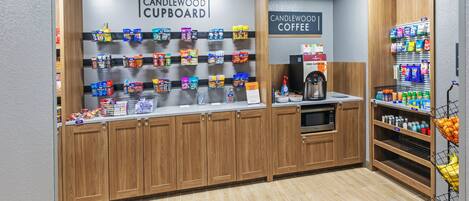 A kitchenette area with a coffee station, a shelf with snacks, and a coffee machine.