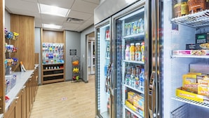 Un supermercado con secciones refrigeradas, estantes llenos de bebidas y una exhibición de bocadillos.