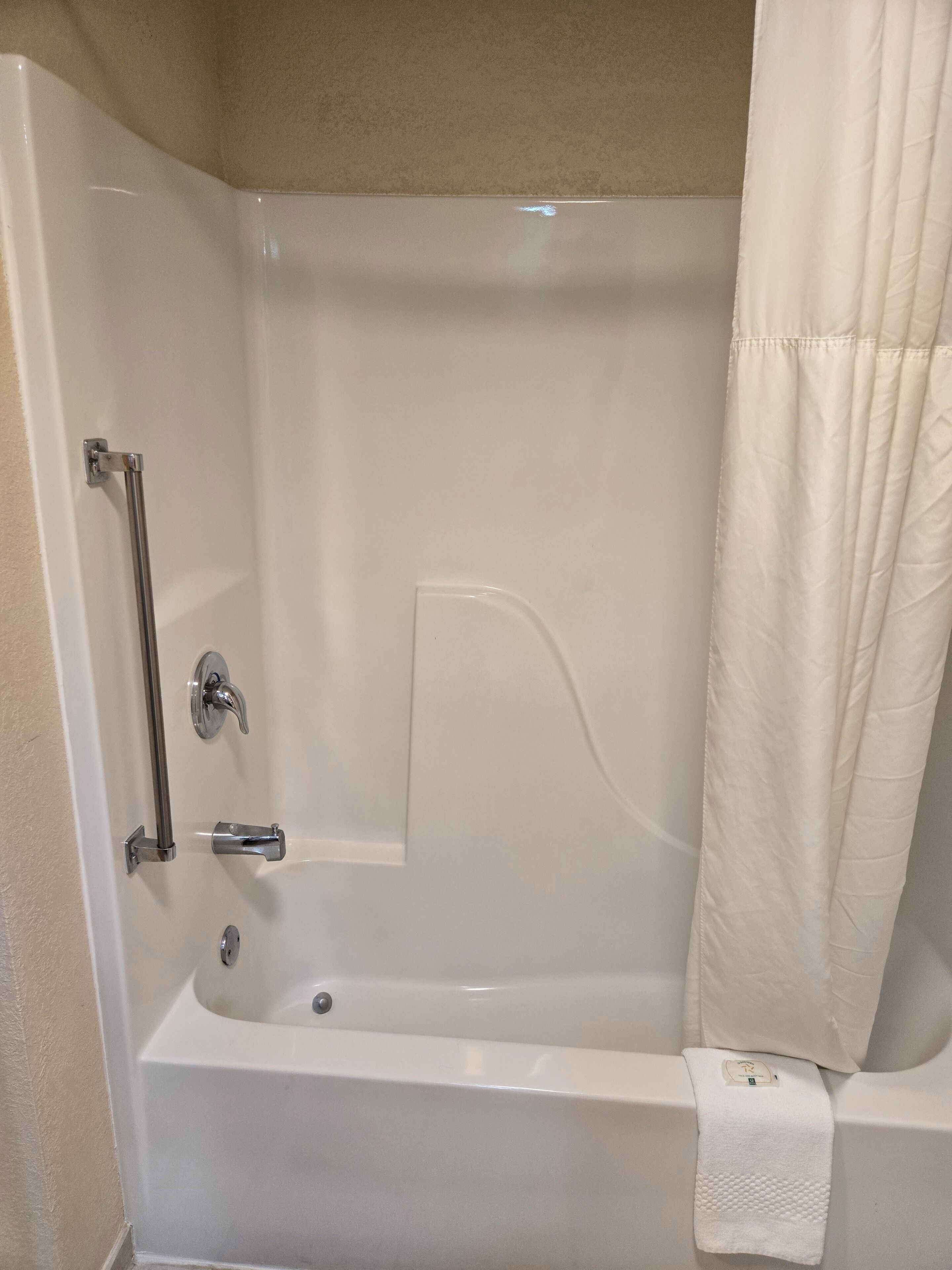 A white bathtub with a shower curtain, a grab bar, and a towel rack.