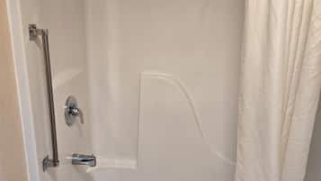 A white bathtub with a shower curtain, a grab bar, and a towel rack.