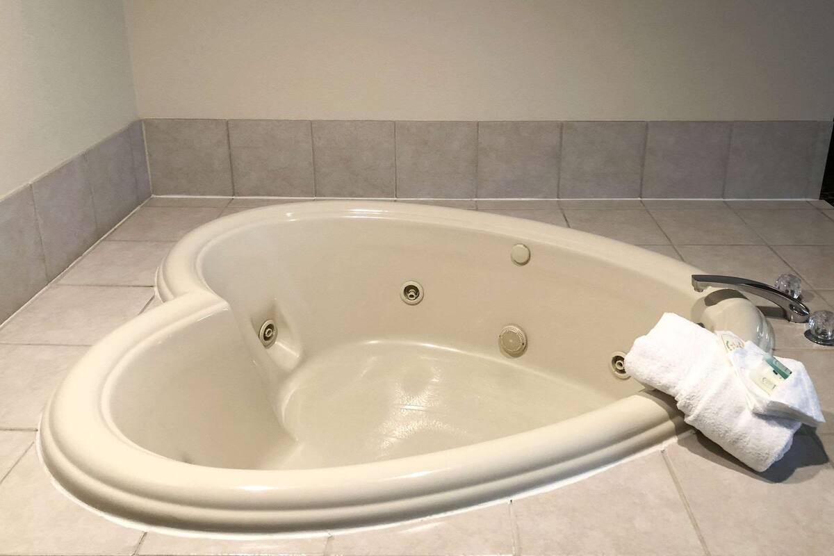 A large, oval-shaped bathtub with a single faucet and two control knobs.
