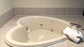 Une grande baignoire de forme ovale, dotée d’un seul robinet et de deux boutons de commande.