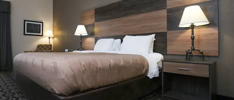 A hotel room with a large bed, two bedside lamps, a nightstand, and a patterned carpet.
