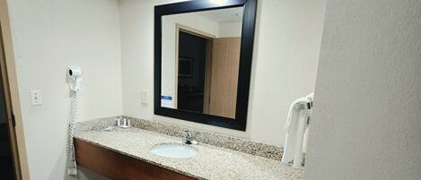 Un baño con lavamanos, espejo e inodoro.