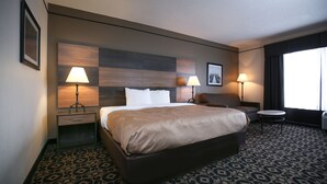 A hotel room with a large bed, two bedside lamps, a small round table, and a patterned carpet. - Quality Inn & Suites Boone - University Area (Boone)