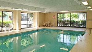 An indoor swimming pool with clear water, surrounded by windows and a table with chairs. - Quality Inn & Suites Boone - University Area (Boone)