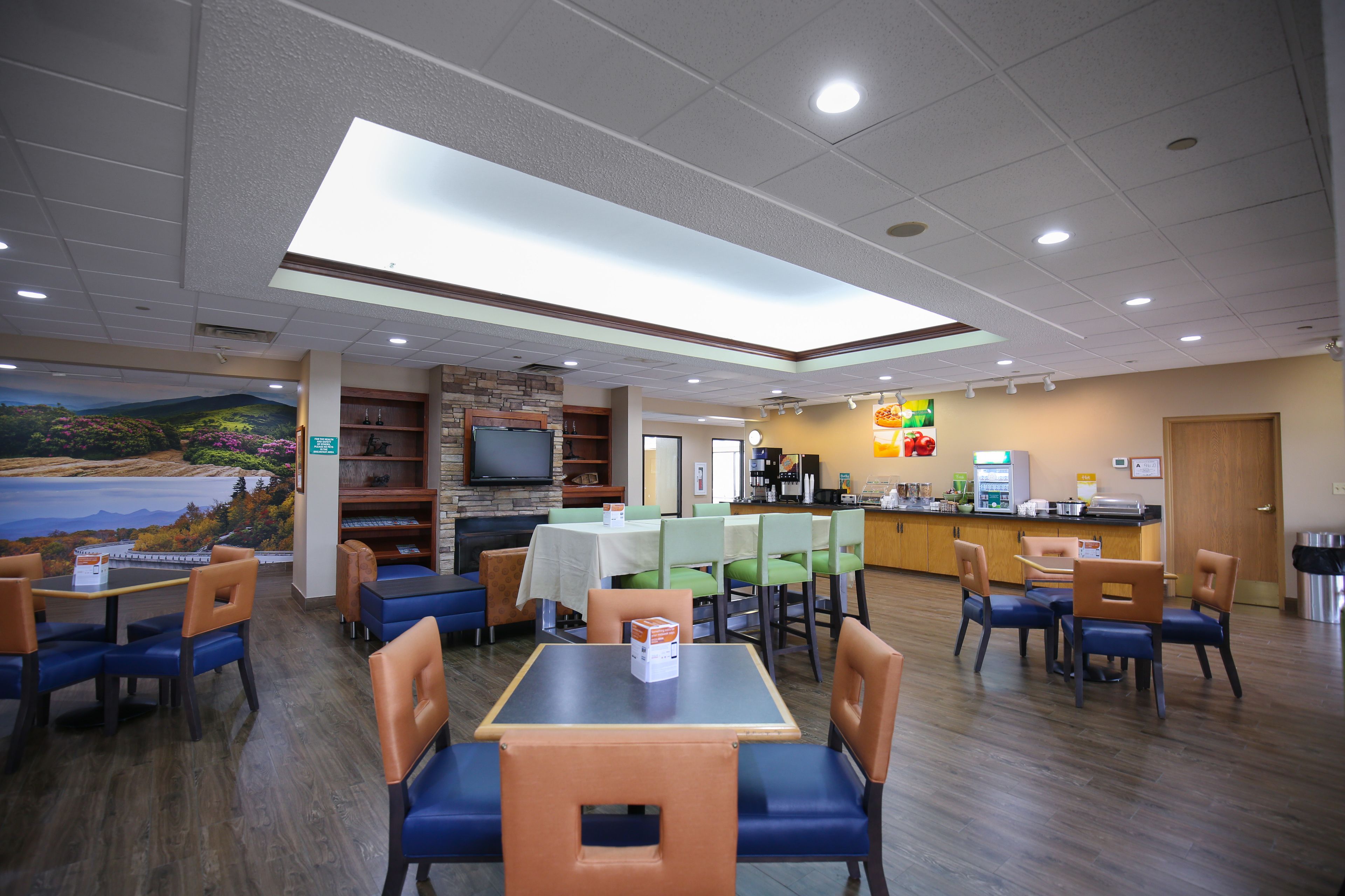 A restaurant with tables and chairs, a counter, and a mural on the wall.