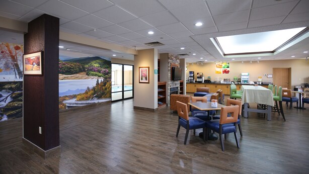 A restaurant with wooden flooring, a mural of a landscape, and a variety of seating arrangements including tables and chairs. - Quality Inn & Suites Boone - University Area (Boone)