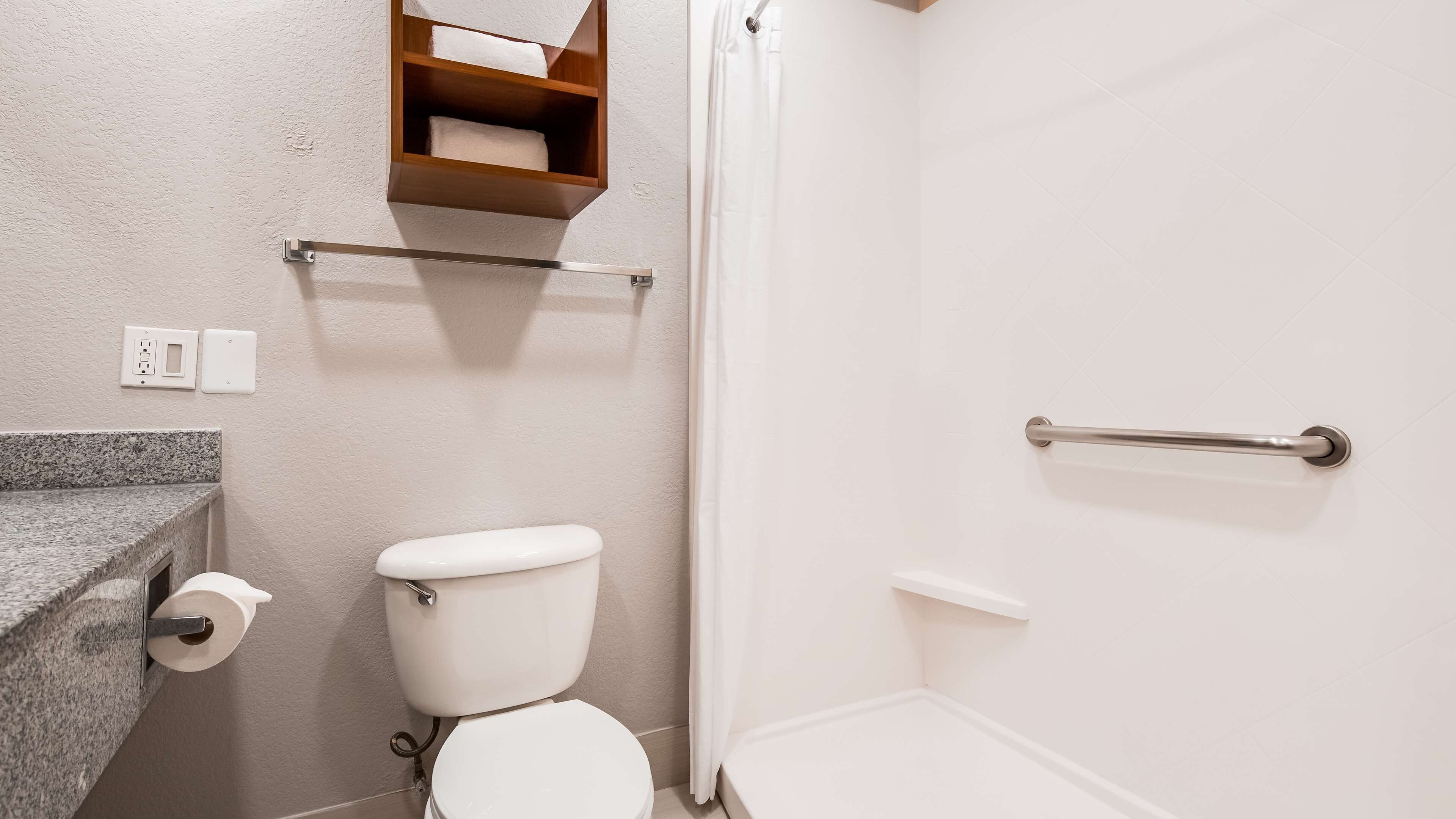 Un bagno con il water, un porta asciugamani e una tenda per la doccia.