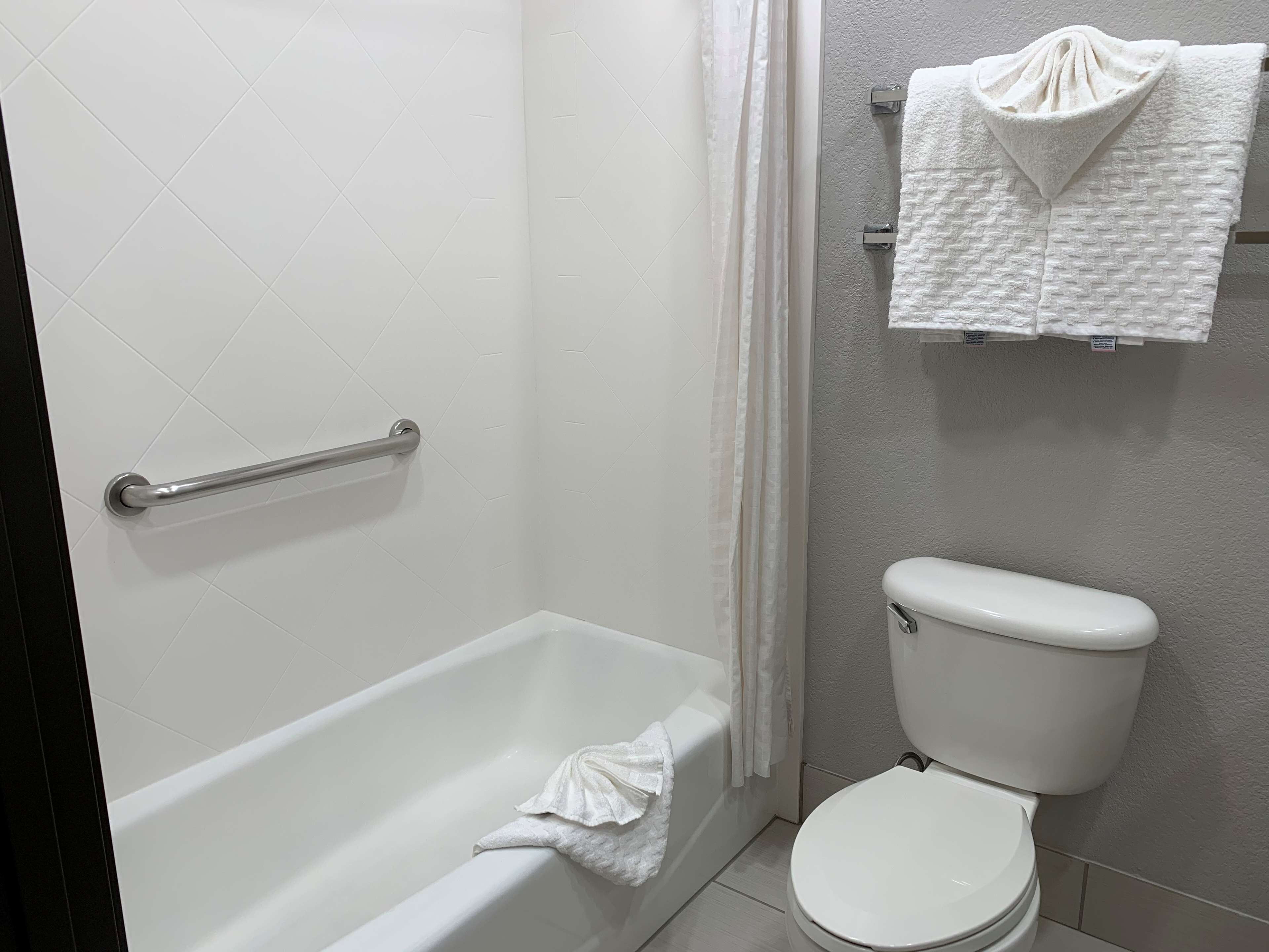 Un baño con bañera, inodoro y toallero con toallas.