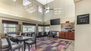 A spacious dining area with high ceilings, large windows, and a complimentary breakfast sign. - Best Western Plus Yukon (Yukon)