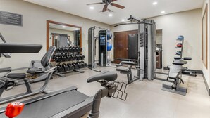 A gym with treadmills, dumbbells, weight machines, and a ceiling fan. - Best Western Plus Yukon (Yukon)