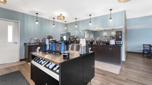 Une cuisine moderne dotée d’un îlot central, de luminaires suspendus et donnant sur la salle à manger.