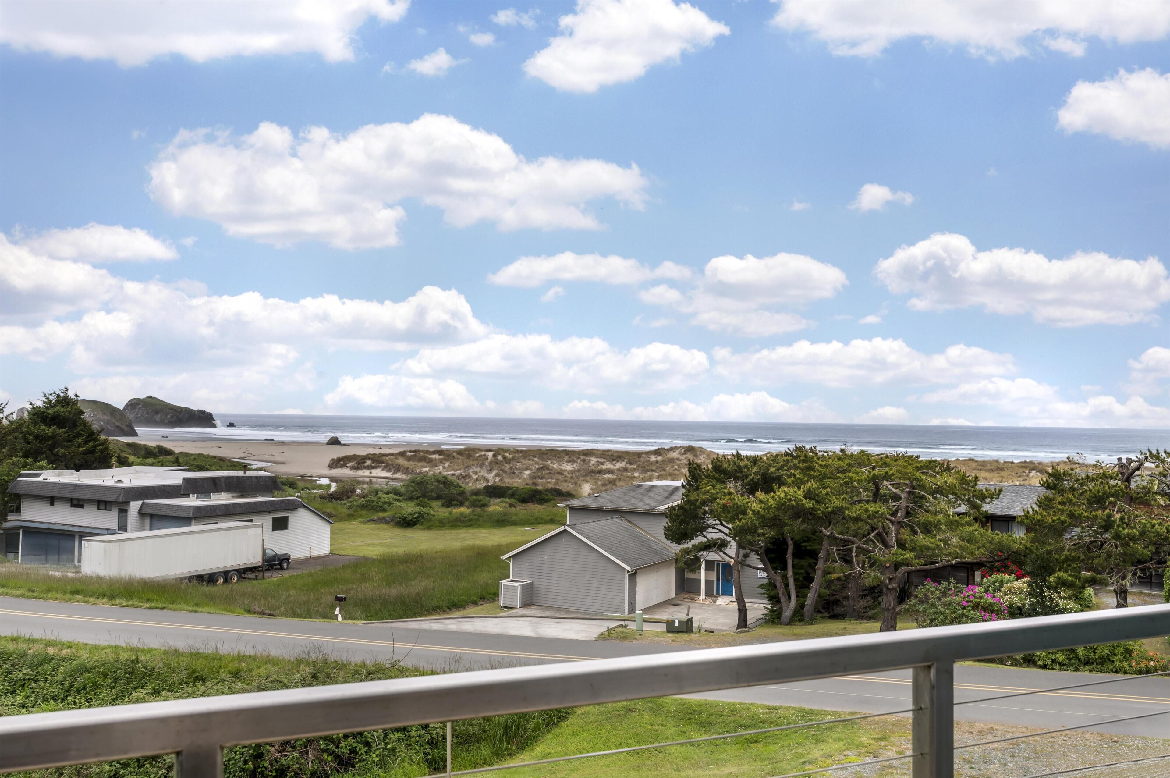 Vista costera con una carretera, una caravana y una pequeña casa con puerta azul.