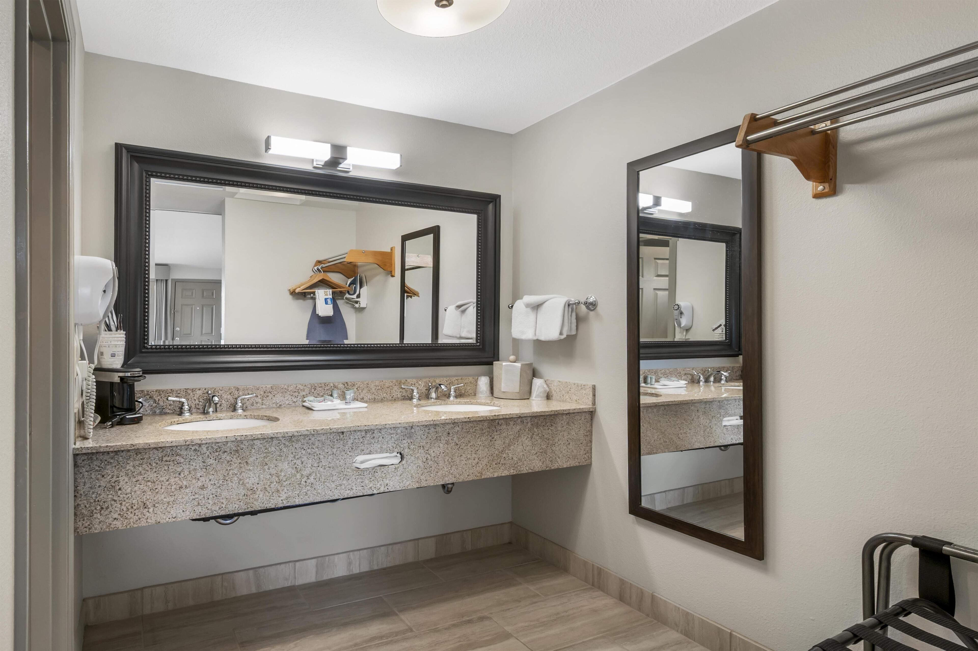 A bathroom with a large mirror, a sink, a towel rack, and a shower area.