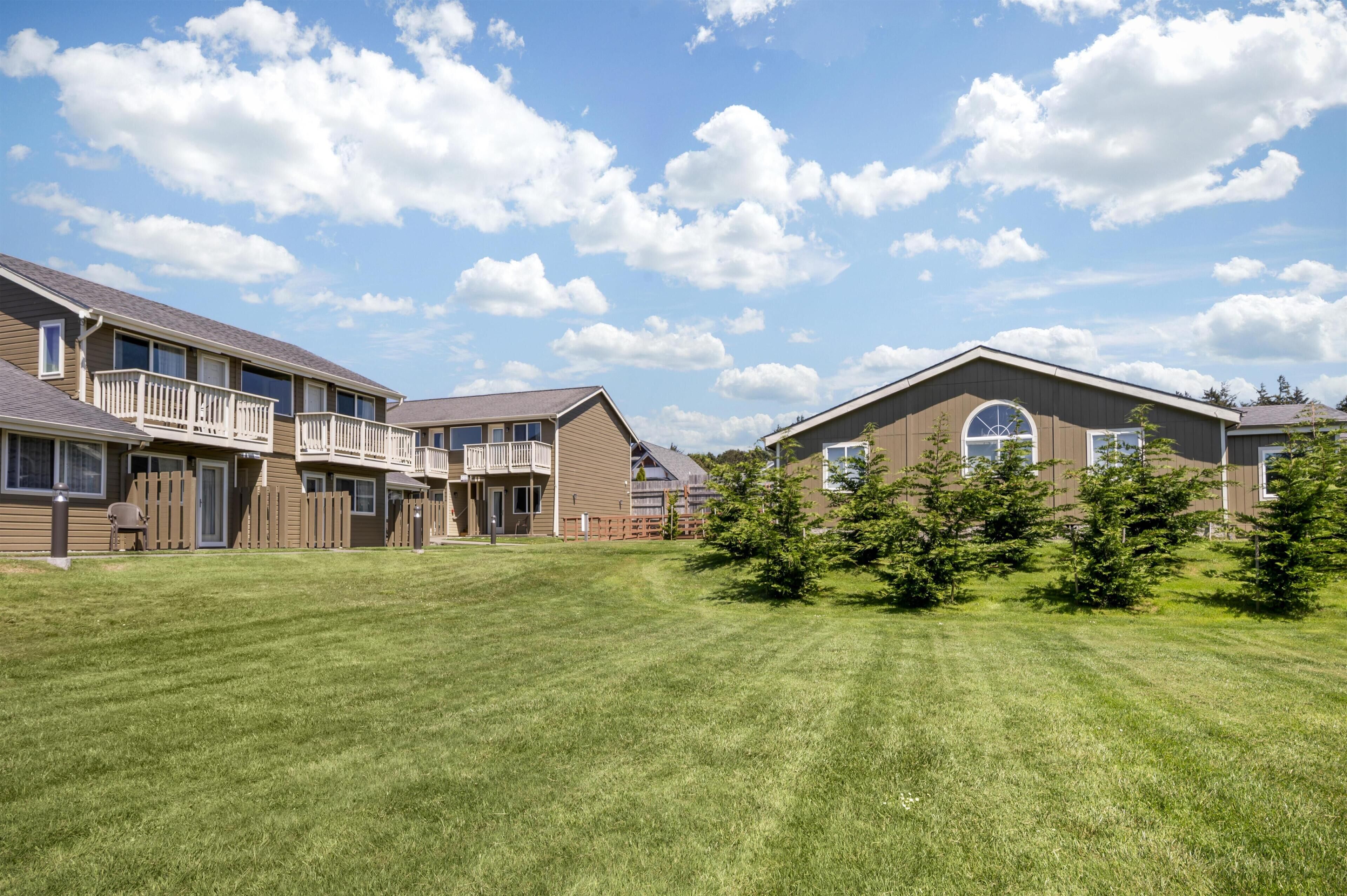 A residential area with houses, a well-maintained lawn, and a clear sky.
