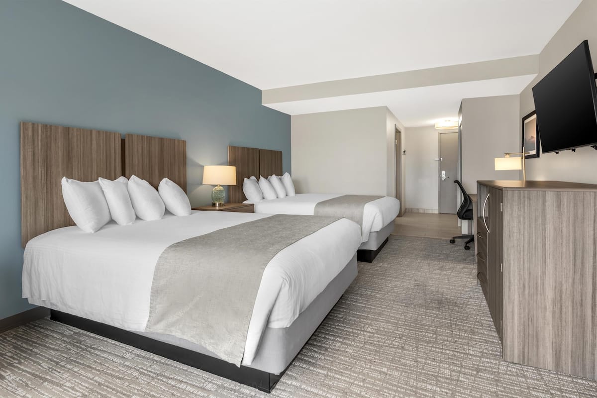Habitación de hotel con dos camas, un escritorio, un televisor y una lámpara.