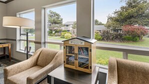 Une pièce avec une grande fenêtre, une bibliothèque, une lampe et une chaise.