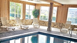 An indoor swimming pool with wooden walls and large windows, surrounded by lounge chairs. - Ashley Inn of Tillamook (Tillamook)