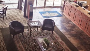 A lobby with a patterned carpet, a reception desk, and a seating area with chairs. - Ashley Inn of Tillamook (Tillamook)