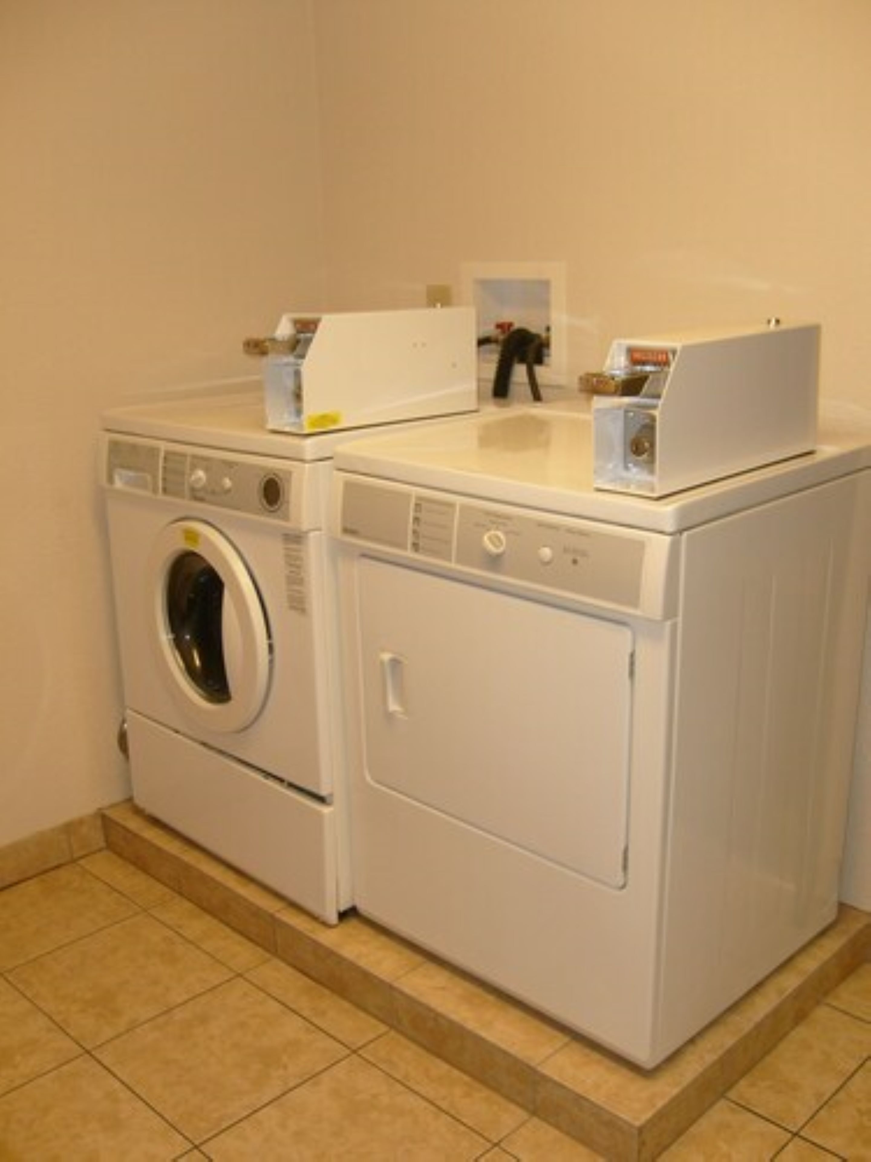 A laundry area with two stacked washing machines and a dryer.
