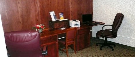 A private office with a wooden desk, two chairs, a printer, and a small plant.
