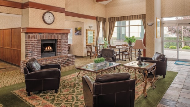 A spacious lobby with a fireplace, leather sofas, a glass coffee table, and a large window offering a view of the outdoors. - Ashley Inn of Tillamook (Tillamook)