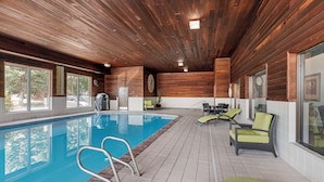 Un espace piscine doté d’un plafond en bois, d’un sol carrelé et de chaises longues.
