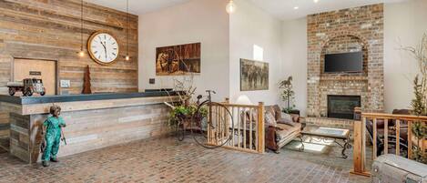 A spacious lobby with a brick floor, wooden reception desk, and a large clock.