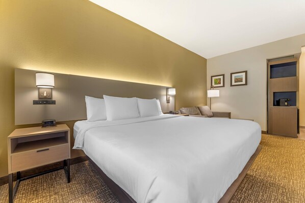A hotel room with a large bed, bedside tables, lamps, a nightstand, and a wardrobe. - Comfort Suites Pittsburgh Airport (Pittsburgh)