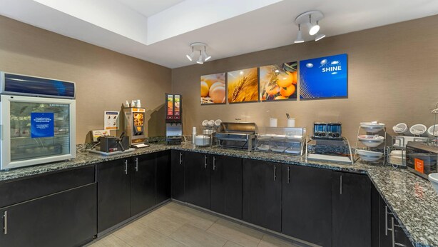 Zona cuina moderna amb espai de petit esmorzar de servei autònom, incloent una màquina de cafè, cereals i presentació de fruita.