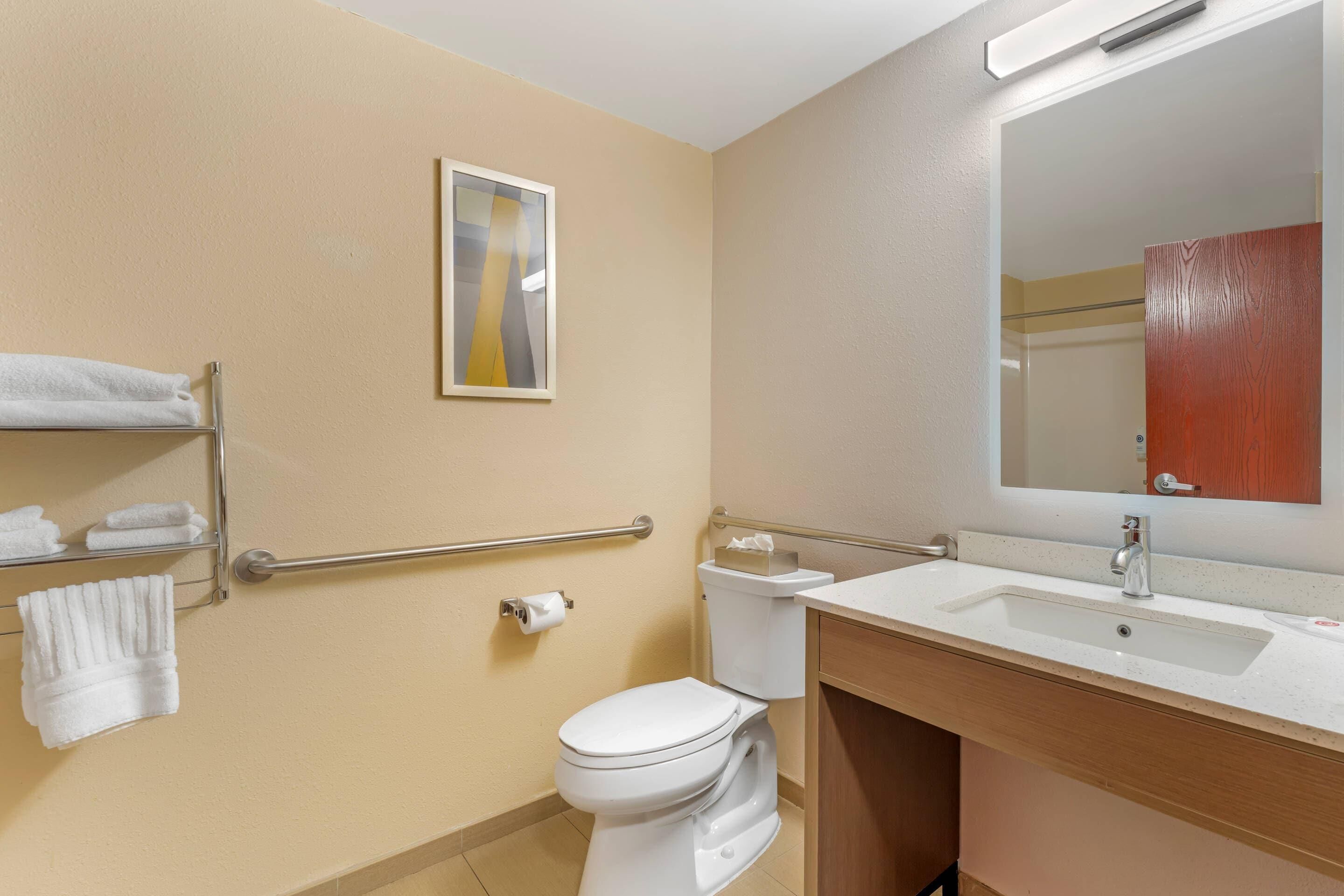 A bathroom with a toilet, sink, towel rack, and a mirror.
