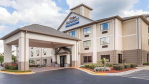 Edificio del Baymont Inn & Suites con entrada cubierta, varias ventanas y un área ajardinada con arbustos y plantas.