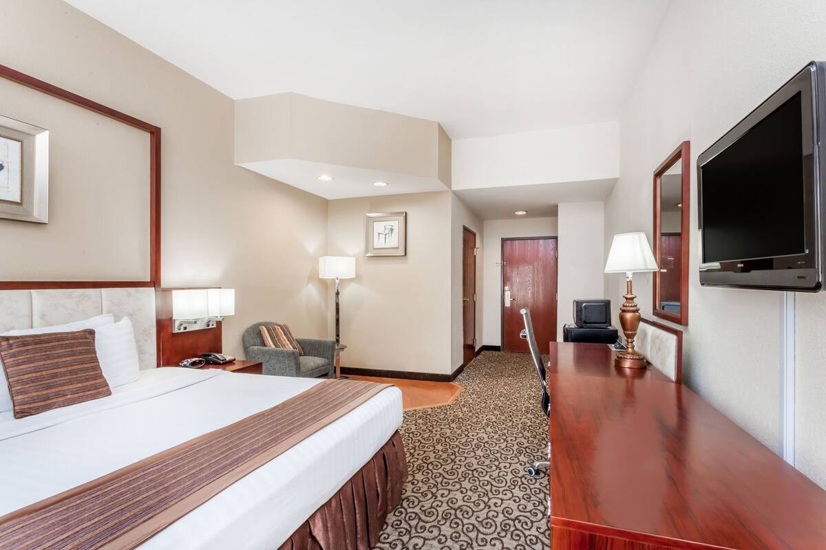 Une chambre d’hôtel avec un lit, un bureau, une chaise, une télévision et une lampe.