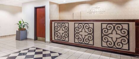 A reception area with a checkered floor, a reception desk with a nameplate, and a potted plant.