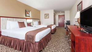 Una habitación de hotel con dos camas, televisión, escritorio y espejo.