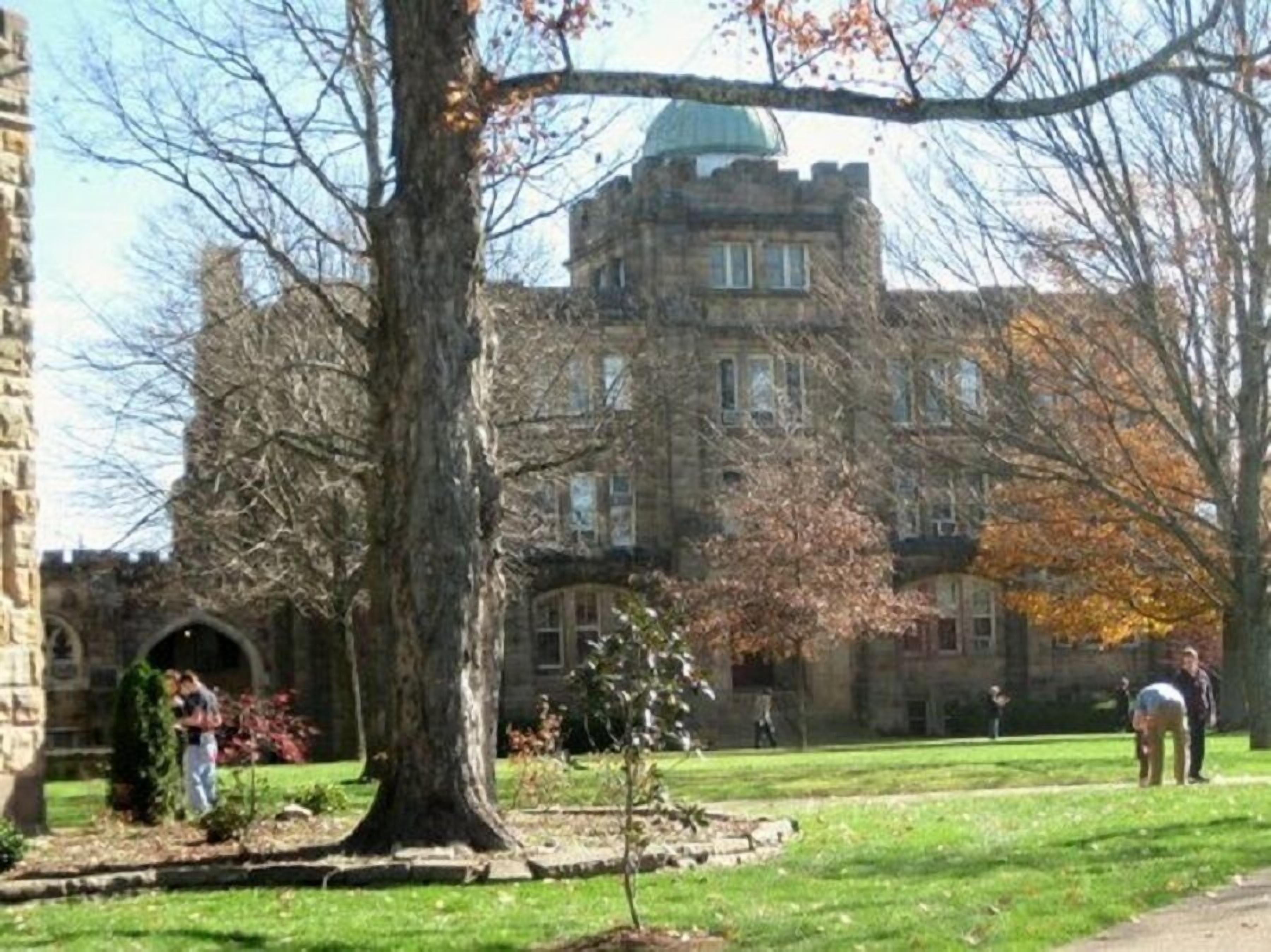 A historic stone building with a central dome, surrounded by a well-maintained lawn and trees.