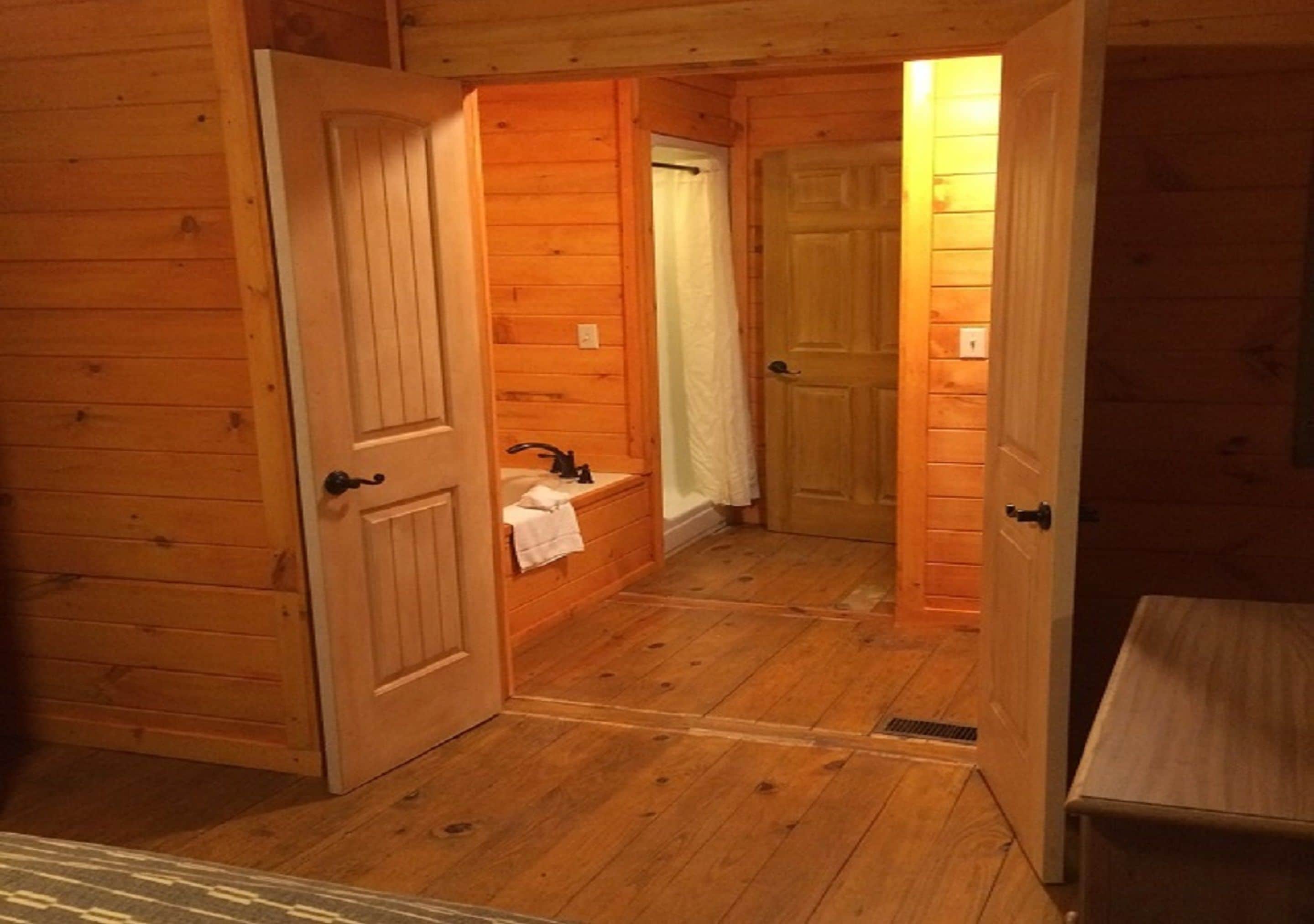 Interior de una cabaña de madera con baño que incluye un lavabo, un inodoro y una ducha.