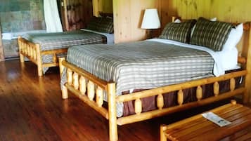 A wooden room with two beds, a wooden bench, and a stone wall.