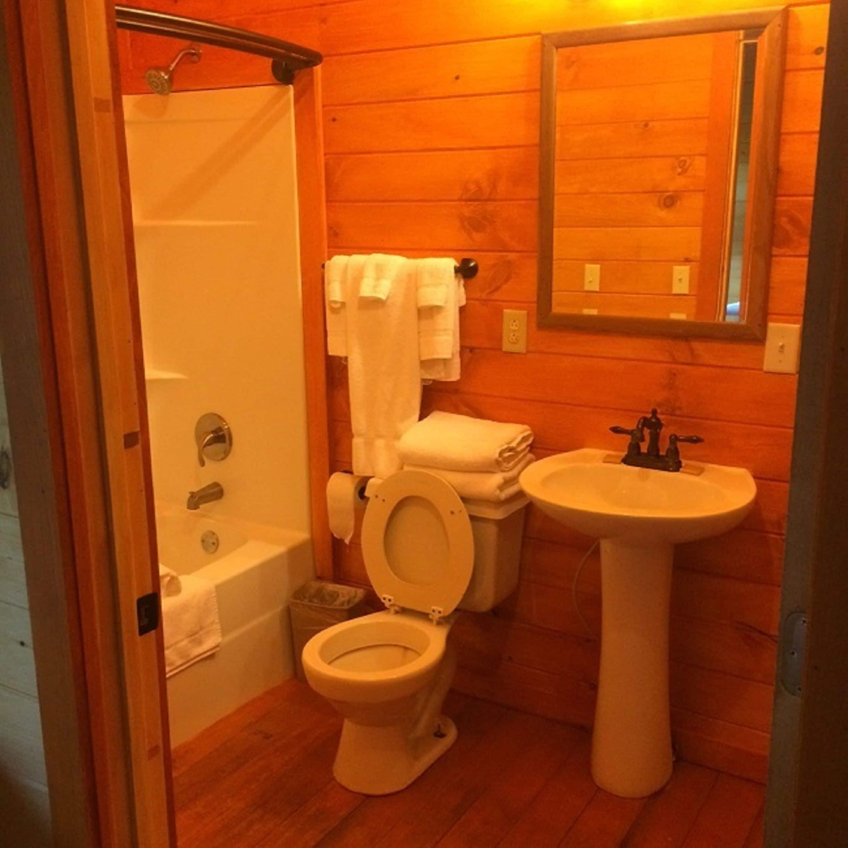 Casa de banho pequena e compacta com sanita, lavatório e chuveiro.