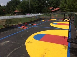 An outdoor basketball court with colorful markings and a hoop. - The Smokehouse Lodge and Cabins (Monteagle)