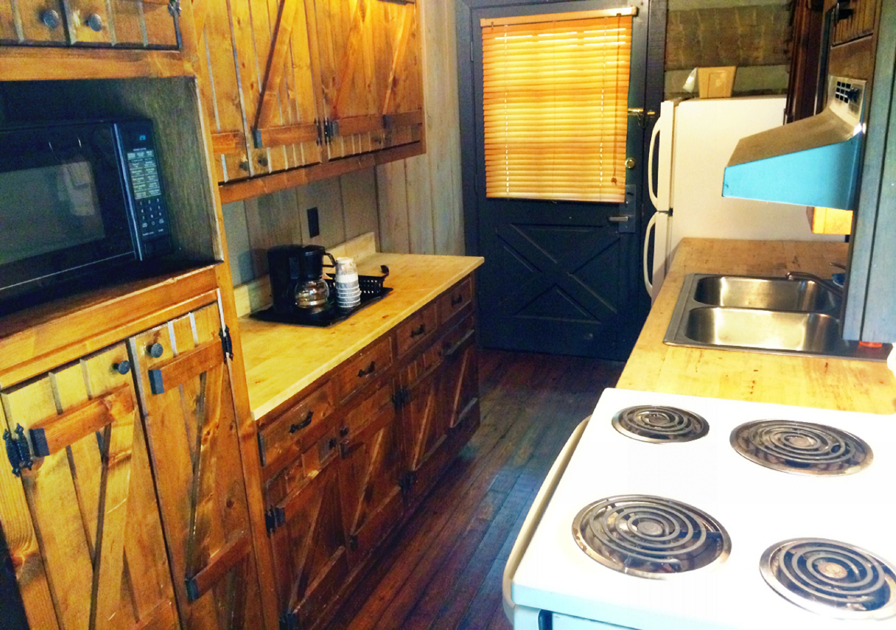 A kitchen with wooden cabinets, a microwave, a stove, and a sink.