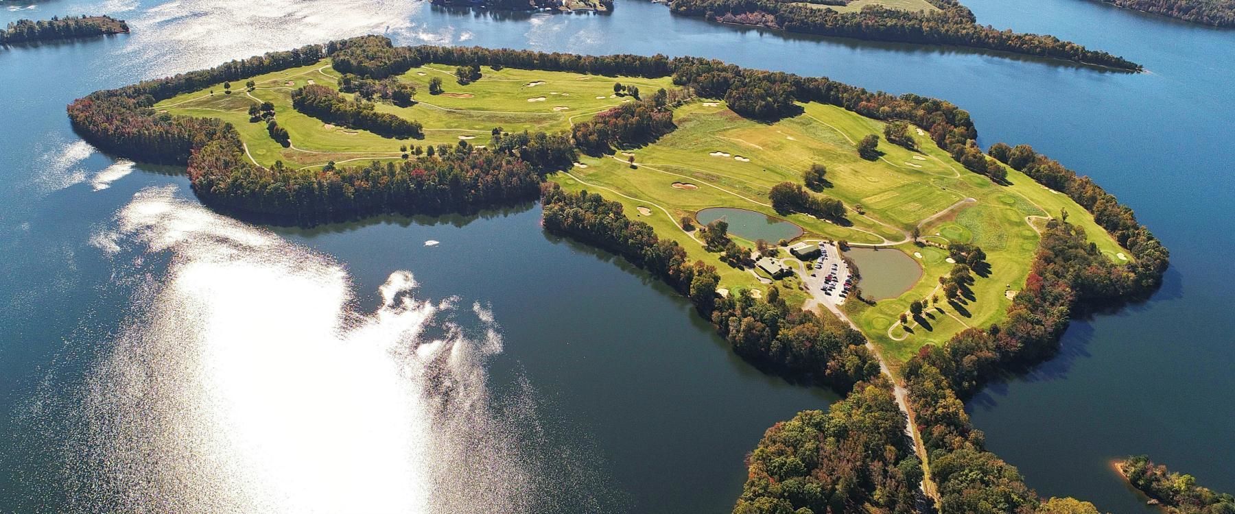 Vista aérea de un campo de golf con varias islas conectadas por puentes, rodeado de agua.