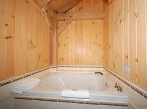 A wooden cabin bathroom with a large bathtub, tiled floor, and a wooden ceiling. - The Smokehouse Lodge and Cabins (Monteagle)