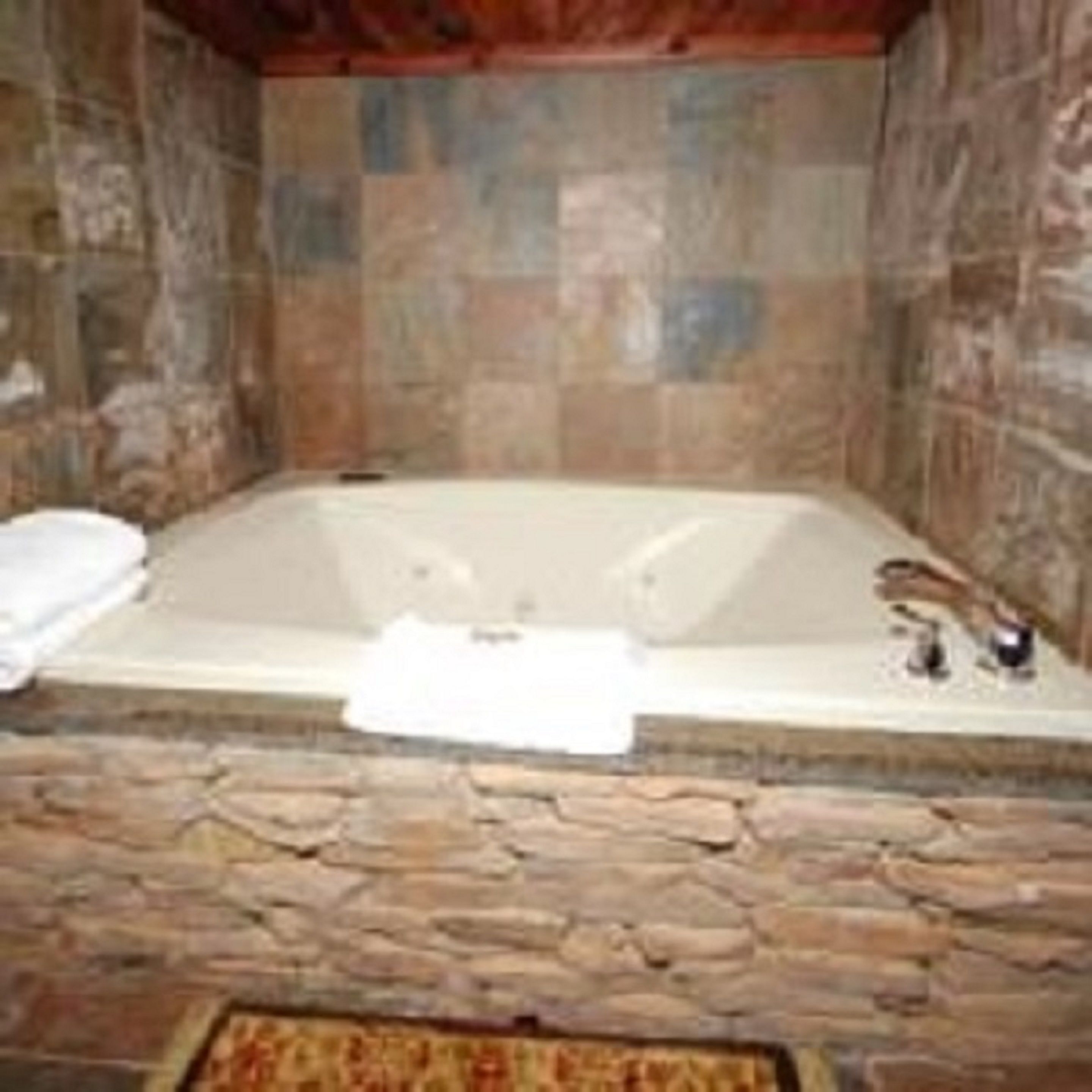 A stone-walled bathroom with a freestanding bathtub.