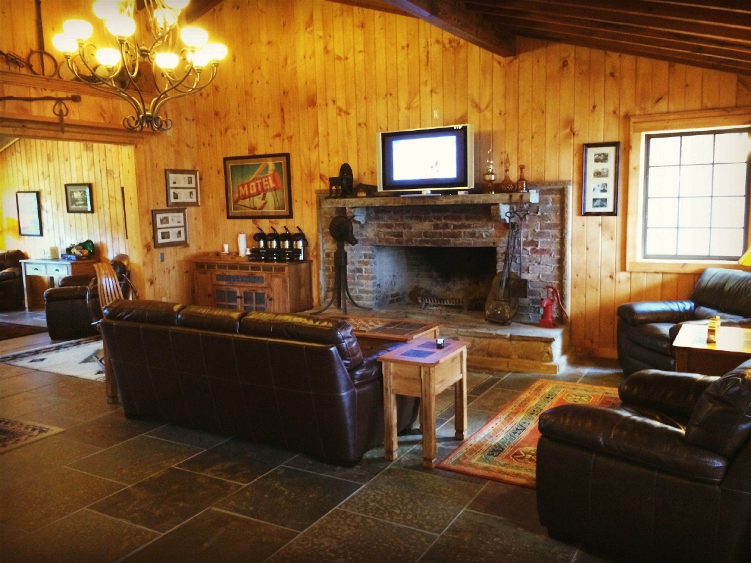 A cozy living room with a fireplace, leather sofas, a television, and a wooden wall.
