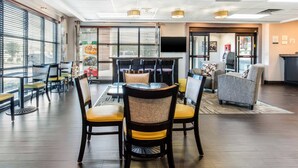 A modern dining area with a high ceiling, large windows, and a variety of seating options including tables and chairs.