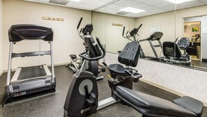 A gym with cardio equipment, a mirror, and a reception area.