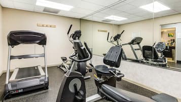 A gym with cardio machines, a mirror, and a reception desk.