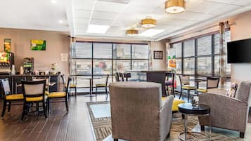 A modern hotel lobby with a bar area, seating, and large windows.